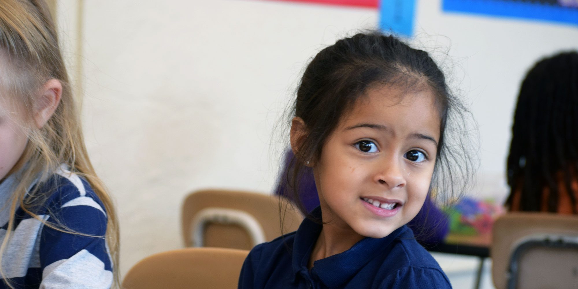 Young student smiling in a classroom.